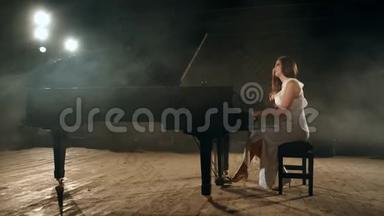 美丽的年轻女子穿着连衣裙在舞台上制作<strong>钢琴音乐</strong>。 4K段
